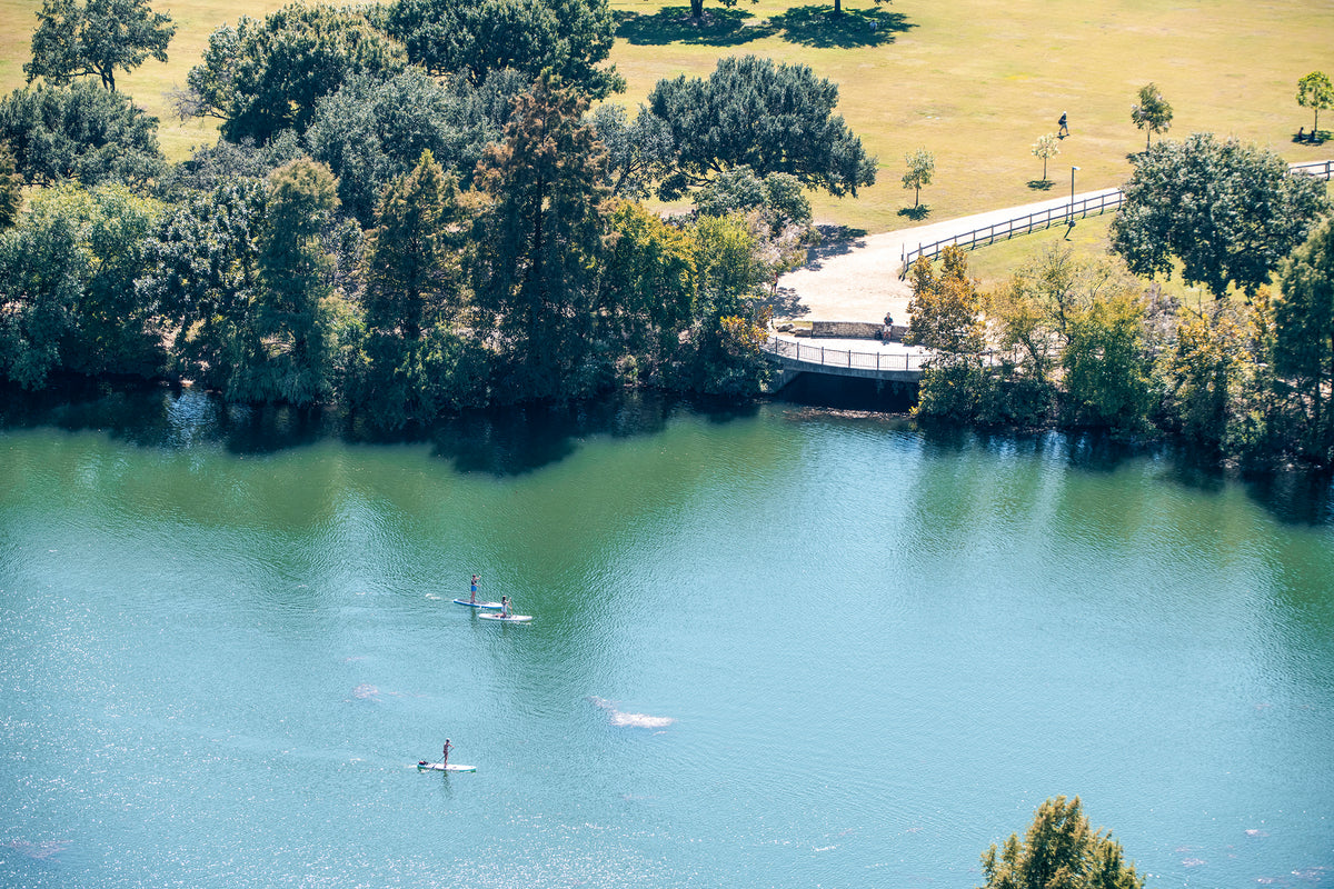 Stand up paddle boarders make their way down Lady Bird Lake on a sunny day