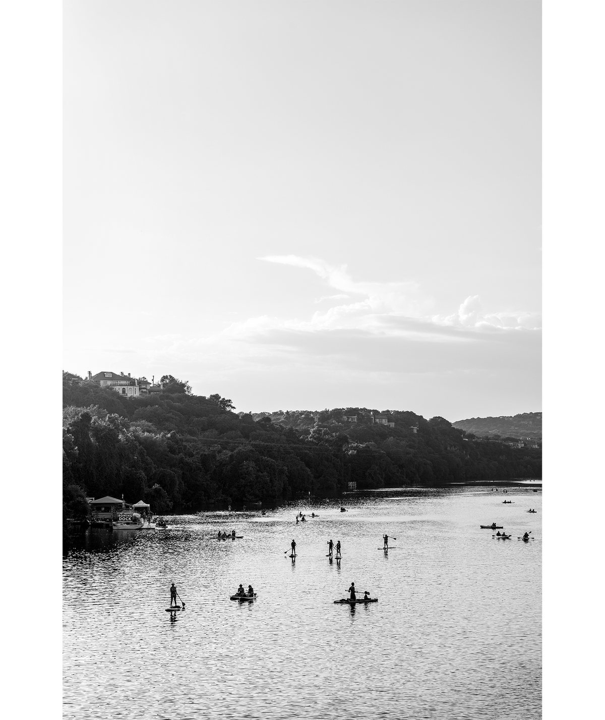 Black and white image of paddle boarders and kayakers on Lady Bird Lake