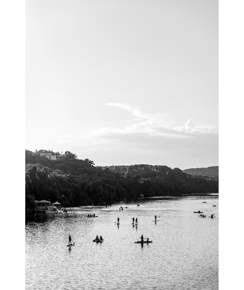 Black and white image of paddle boarders and kayakers on Lady Bird Lake