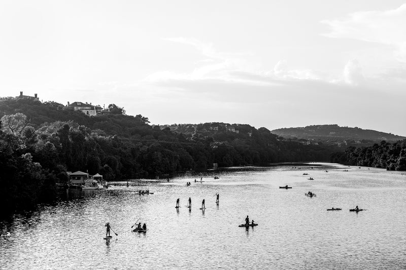 Black and white image of kayakers and paddle boarders on Lake Austin