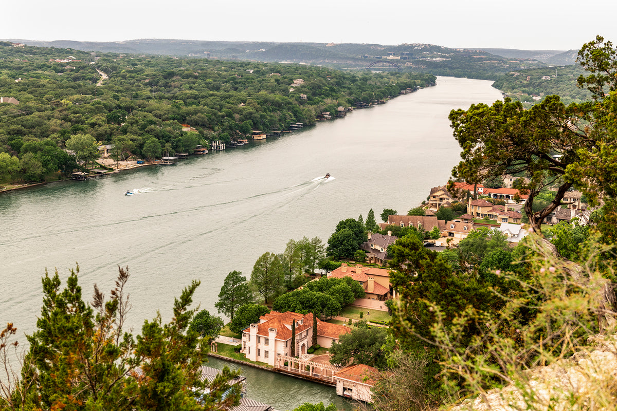 Two boats travel along Lake Austin as seen from the top of Mount Bonnell